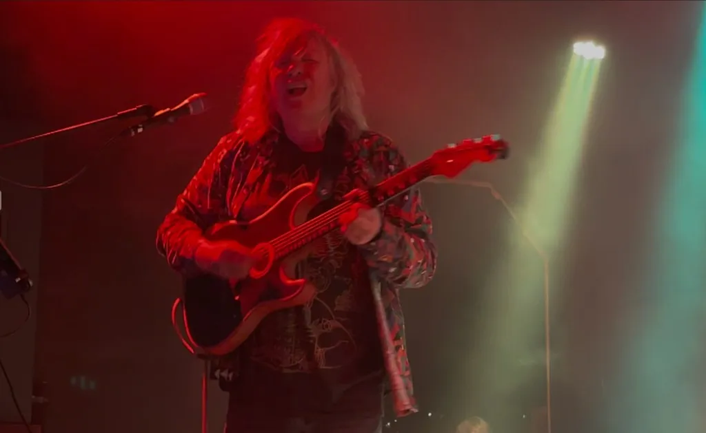 Mannie Live singt und spielt Akustikgitarre, rotes und grünes Bühnenlicht mit Nebel